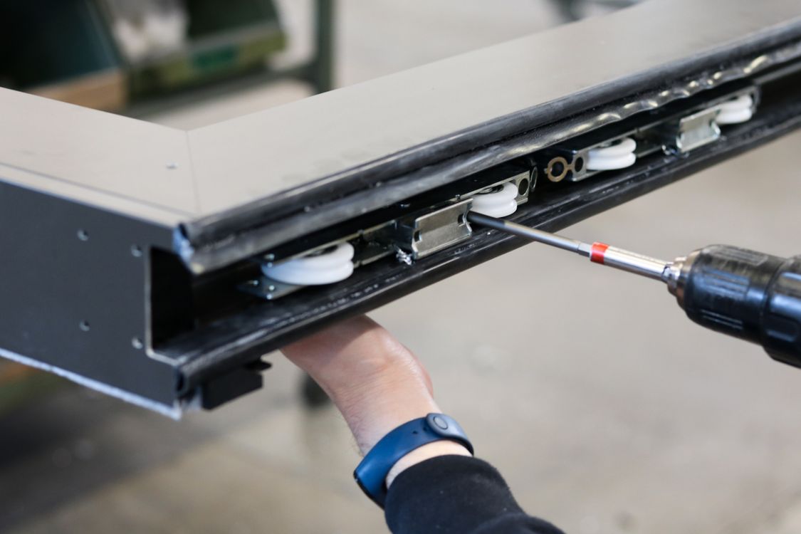 Worker fastening rollers and brackets into a metal rail assembly
