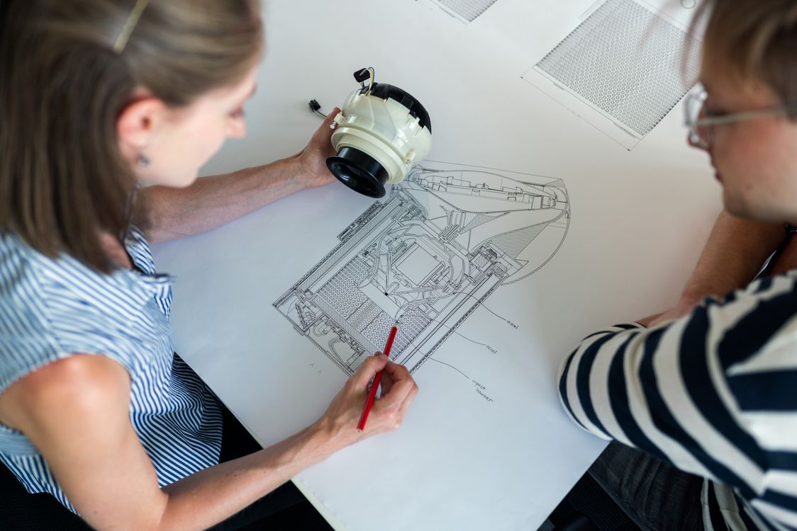 Engineers reviewing a mechanical component and technical drawings